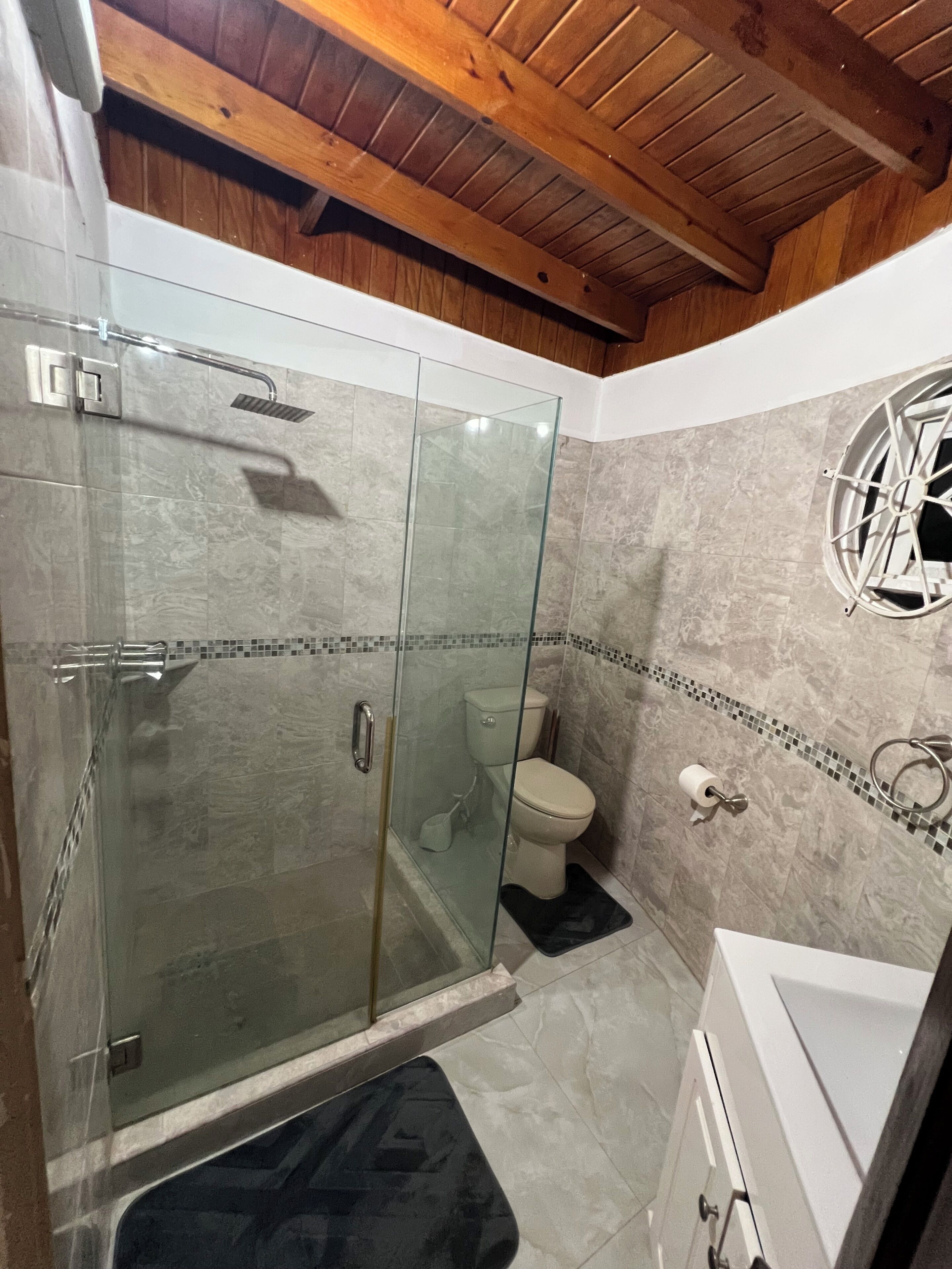 A bathroom with a glass-enclosed shower, a toilet, and a bathtub.
