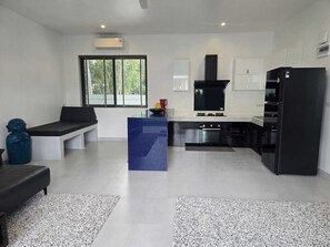 A modern kitchen with a central island, built-in appliances, and a large window providing natural light. - Buddha Bliss Luxury Villa (Tambon Ko Pha-Ngan)