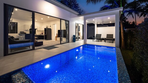 A modern house with a swimming pool, large glass doors leading to a living area, and a view of palm trees. - Buddha Bliss Luxury Villa (Tambon Ko Pha-Ngan)
