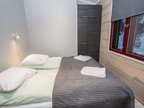 Une chambre avec deux lits, une armoire et une fenêtre donnant sur des arbres.