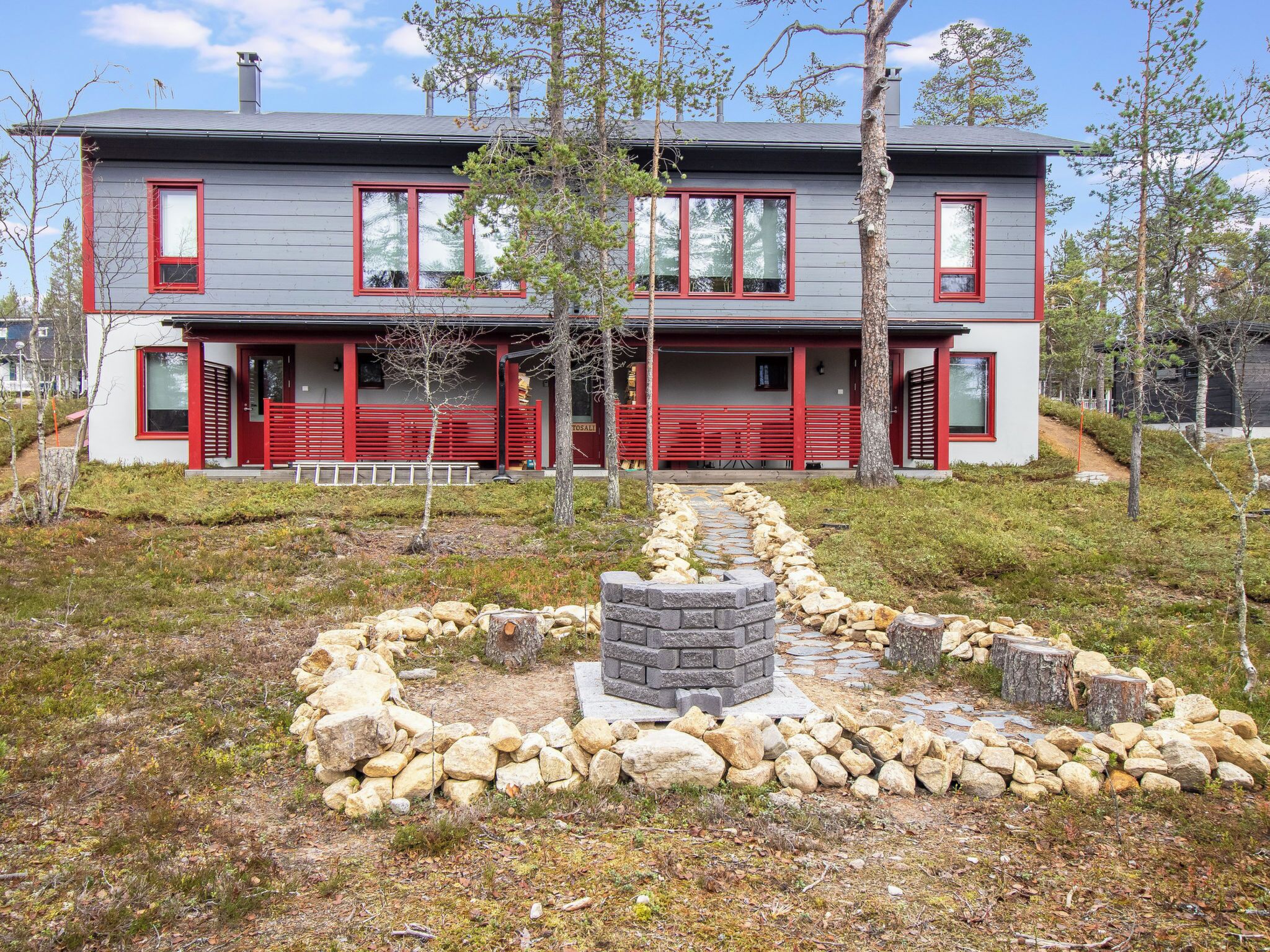 A modern two-story house with a stone pathway leading to a wooden deck.