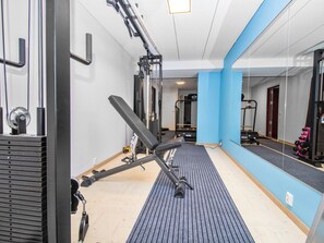A gym with exercise equipment, a mirrored wall, and a blue accent wall. - Tuiskukuru b by Interhome (Inari)