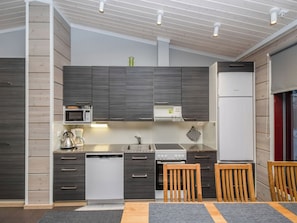 Een moderne keuken met inbouwapparatuur, houten kastjes en een eethoek met een tafel en stoelen.