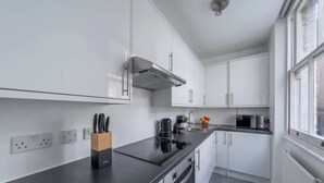 Een moderne keuken met witte kasten, een zwart aanrecht, een ingebouwde kookplaat en een raam dat natuurlijk licht binnenlaat.