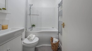 Een kleine badkamer met toilet, bad en douche.