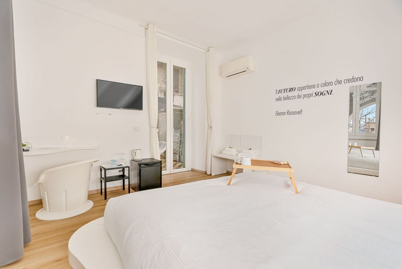 Une chambre d’hôtel moderne équipée d’un lit, d’un bureau, d’une chaise, d’une télévision et d’une fenêtre donnant sur un paysage agréable.