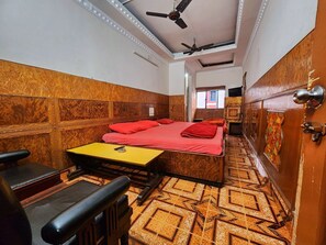Habitación de hotel pequeña con cama, una mesita, una silla, ventilador de techo y piso estampado.