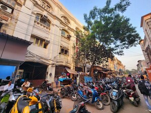 A street with parked motorcycles and a building with multiple stories and balconies. - Meena Guest House  (Kolkata)