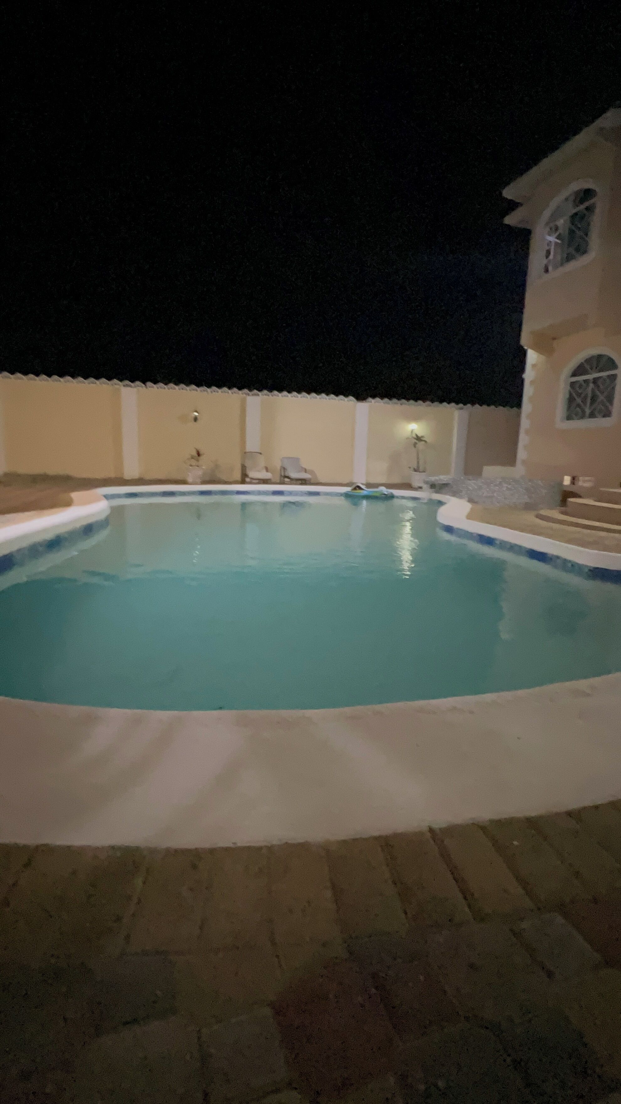 A swimming pool with a tiled deck surrounding it.