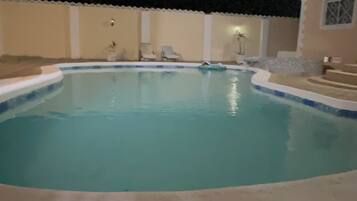 A swimming pool with a tiled deck surrounding it.