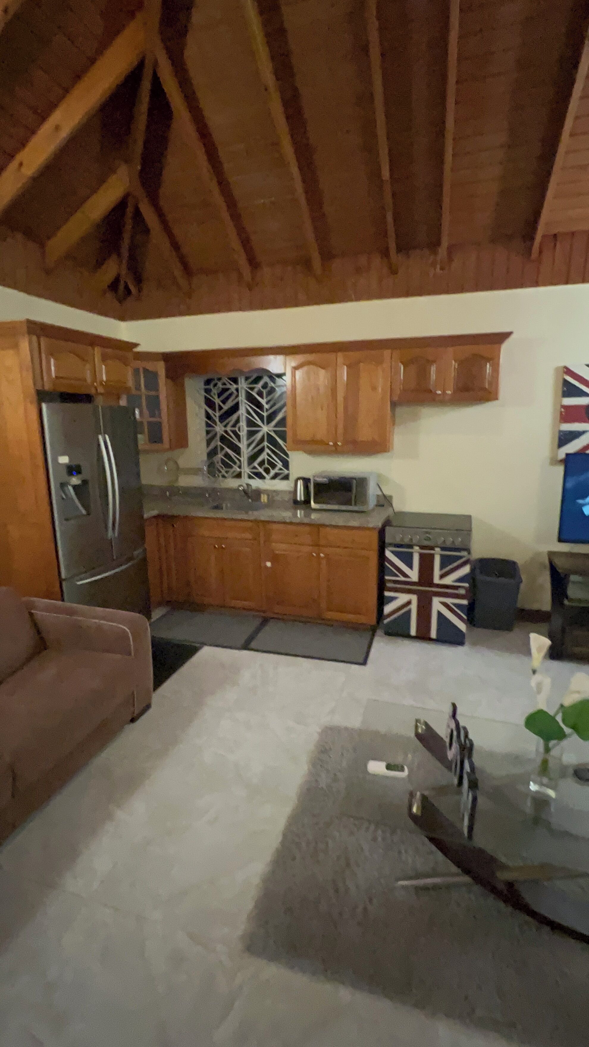 A compact kitchen with wooden cabinets, a stainless steel refrigerator, a microwave, and a stove.
