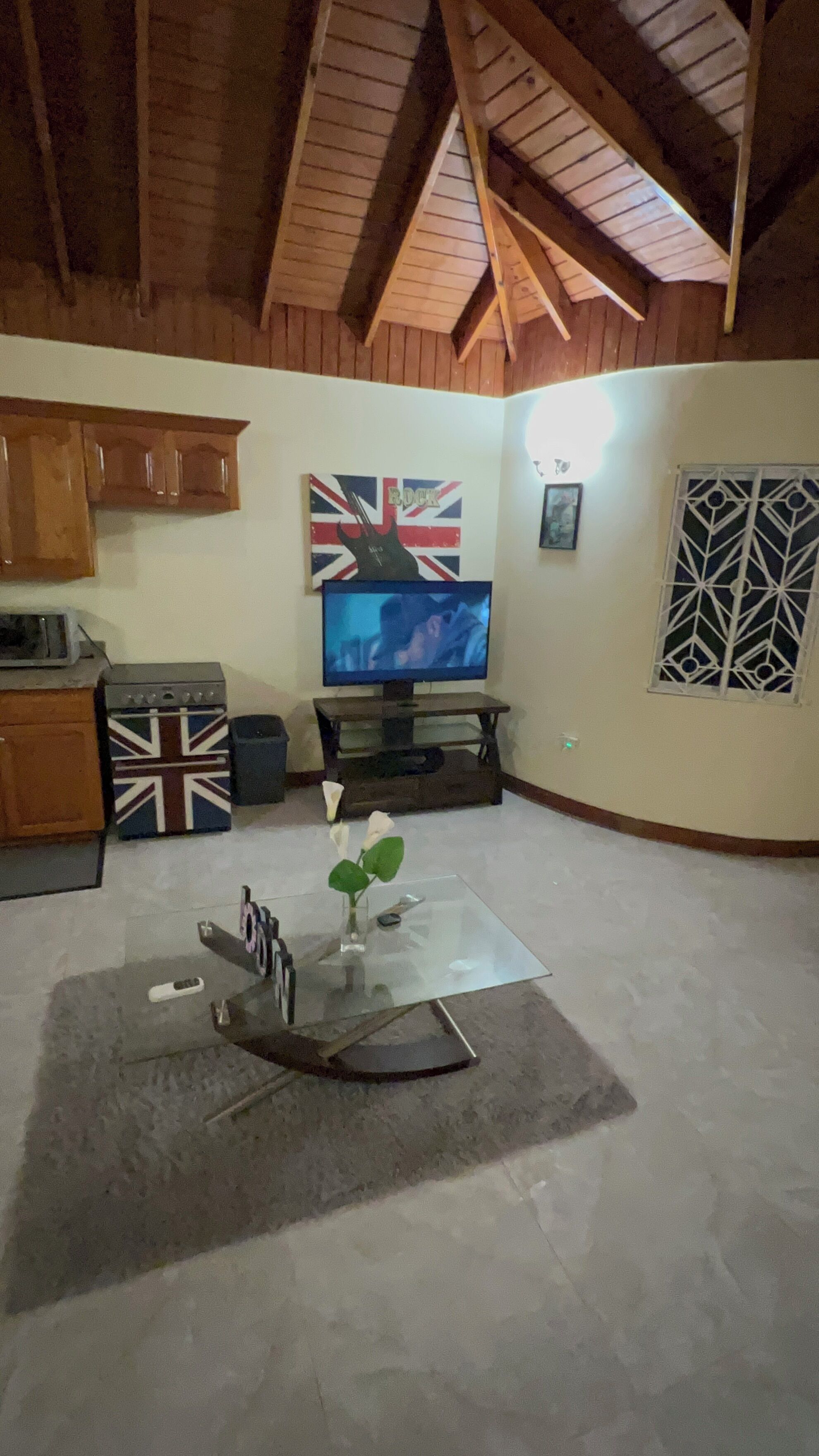 A living room with a television, a table with a vase, and a flag-patterned cabinet.