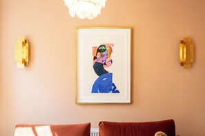 Ein gerahmtes Kunstwerk an der Wand, ein Heizkörper und zwei braune Kissen auf einer Couch.
