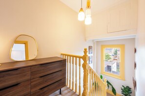 Uma escada com corrimão de madeira, um aparador de madeira e um espelho na parede.