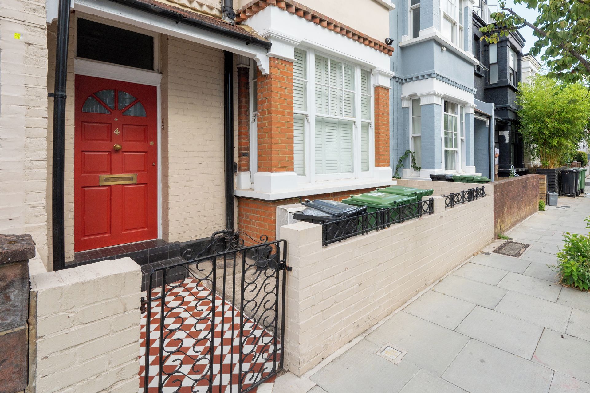 A row of terraced houses with a red door, white window frames, and a patterned metal gate.