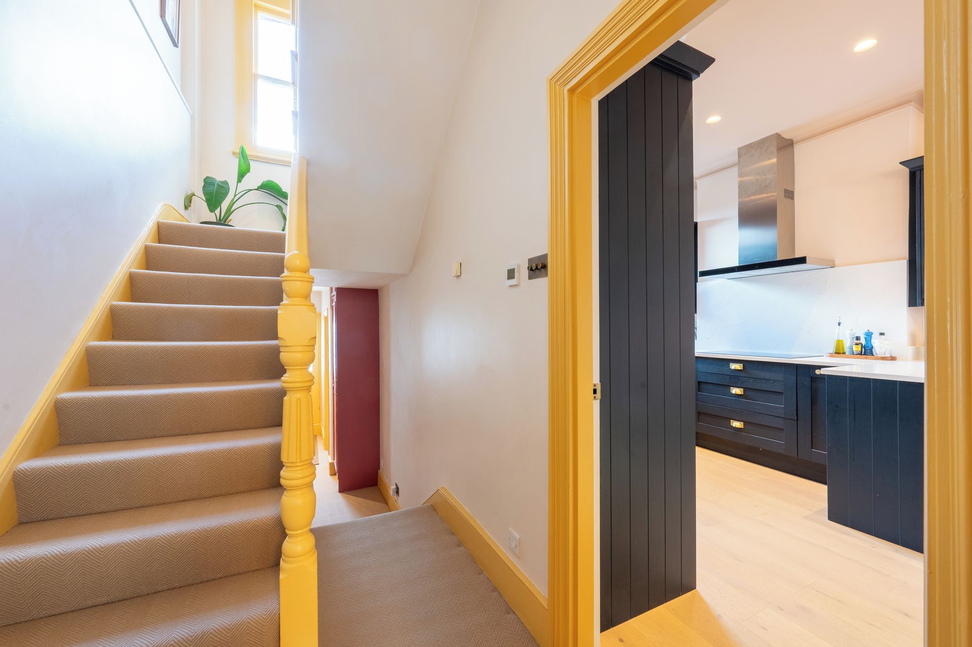 A staircase with a carpeted finish leading to a room with a kitchen area.