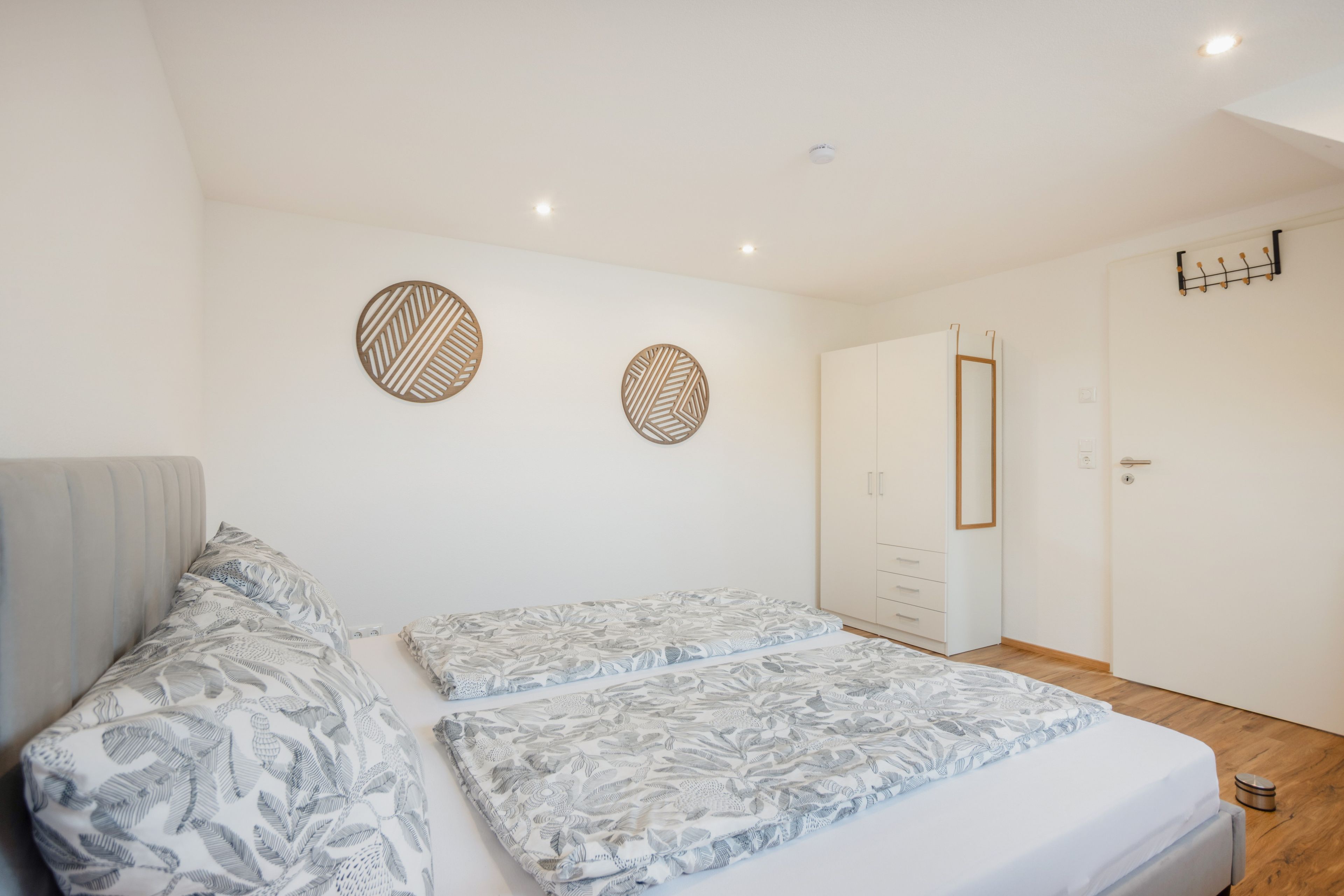 A bedroom with two beds, a wardrobe, and a coat rack.