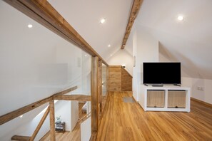 Ein modernes Interieur mit einer Holztreppe, einem Flachbildfernseher auf einem weißen Schrank und Holzboden.