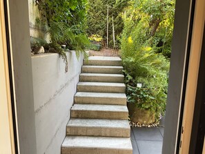 A concrete staircase leading to a garden area with various plants and a small pond. - Apartment with a terrace in the heart of nature (Avenches)
