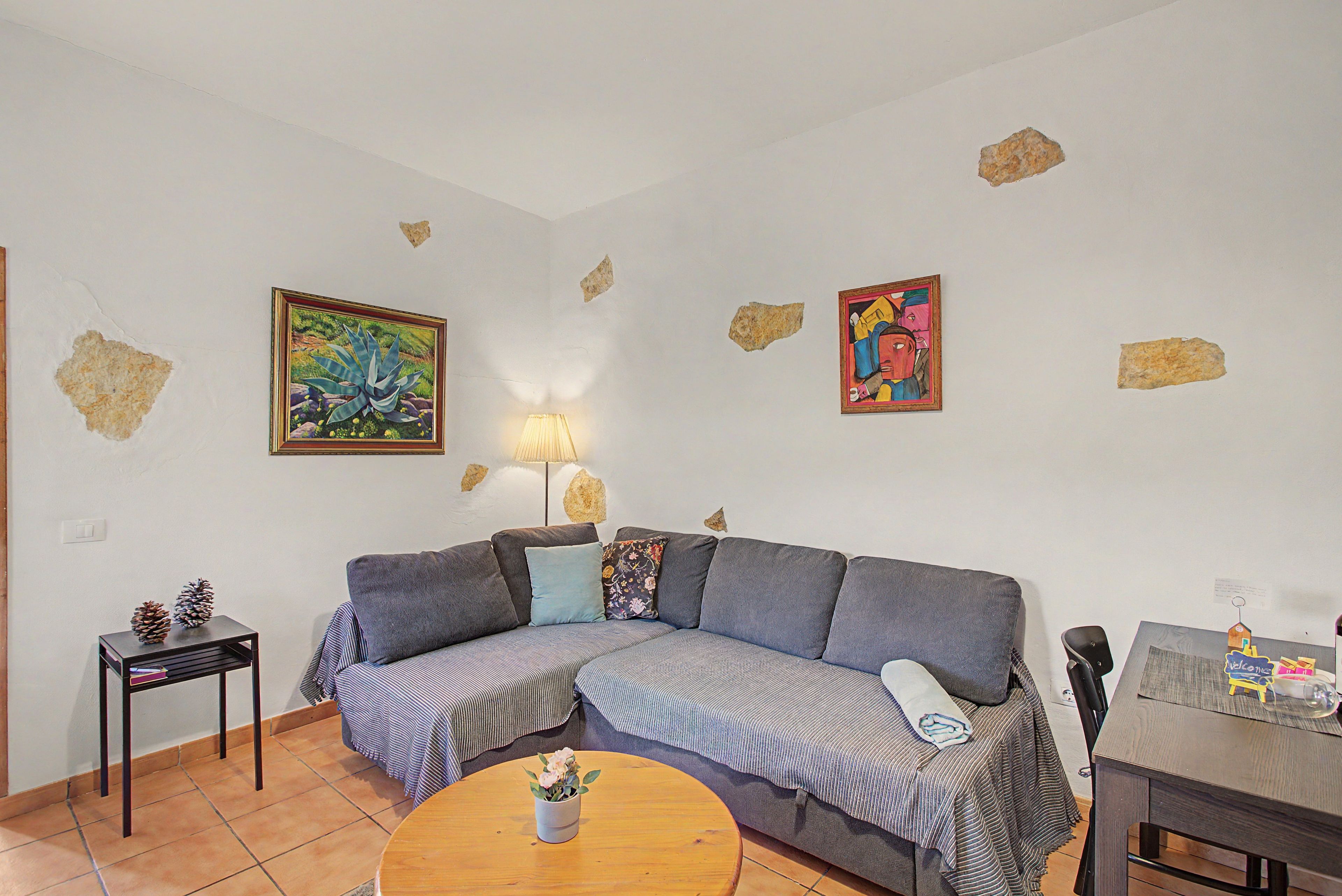 A living room with a sofa, a coffee table, a lamp, and two paintings on the wall.