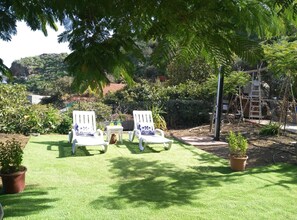 A garden with two white chairs, a small table, and potted plants.