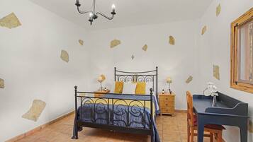 Un dormitorio con cama, escritorio, silla, lámpara y candelabro.