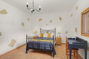Ett sovrum med en säng, ett skrivbord, en stol, en lampa och en kristallkrona.
