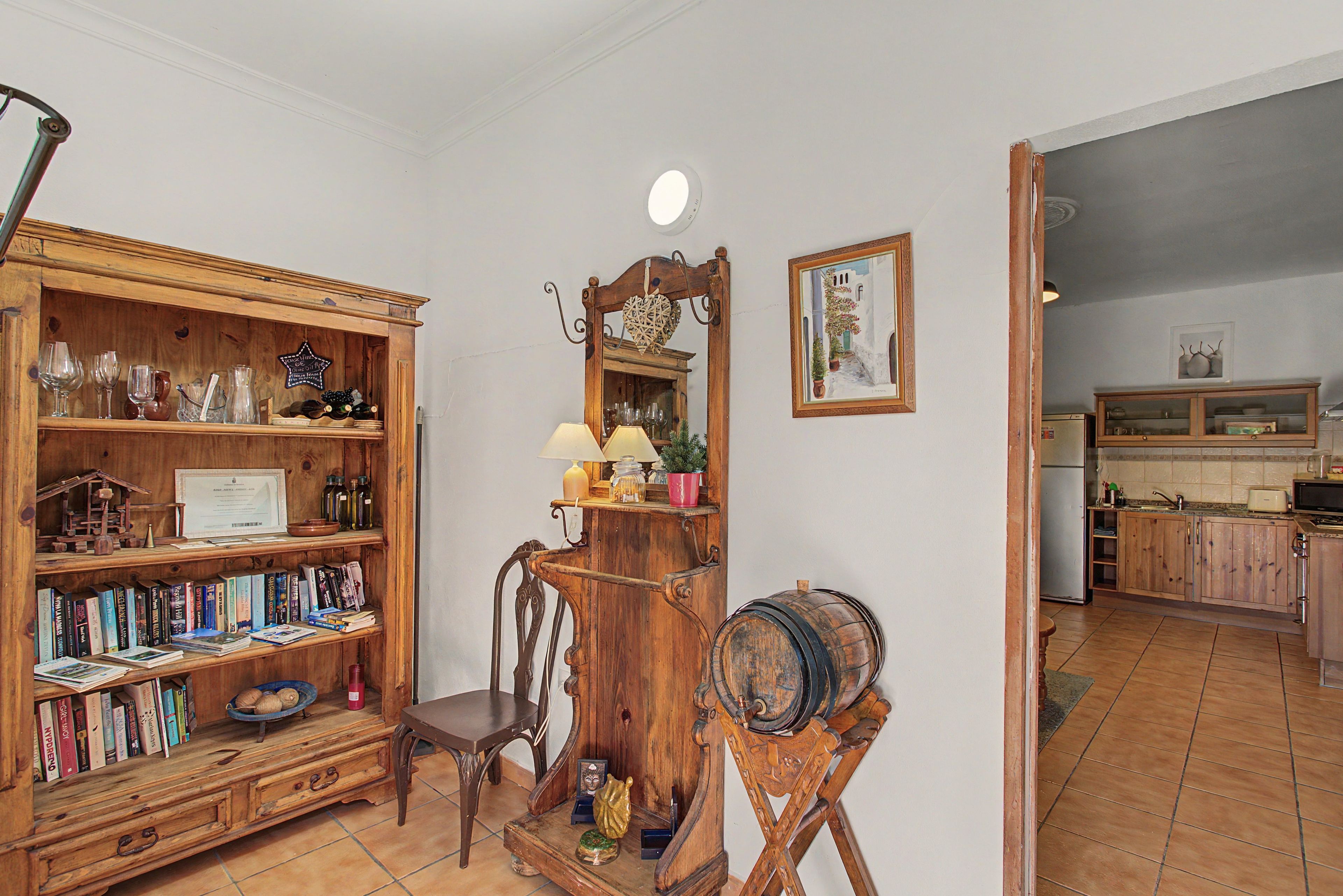 A room with a wooden bookcase, a mirror, a chair, and a barrel.
