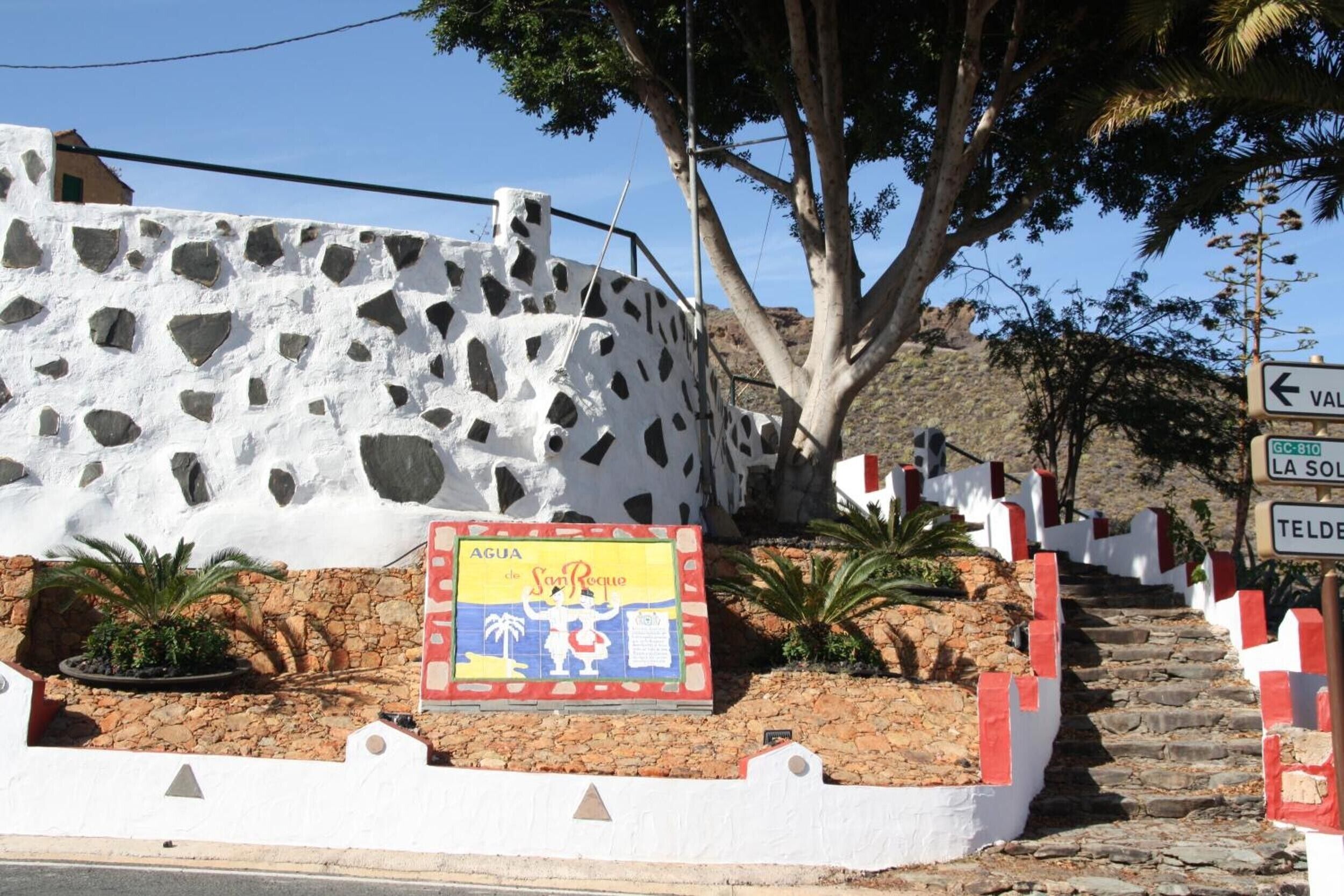 Un edificio blanco con fachada de piedra y un letrero que dice 'AGUA de San Roque'.