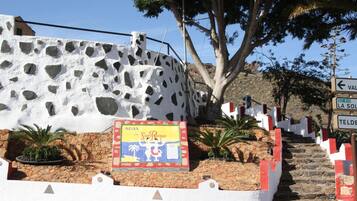 Un edificio blanco con fachada de piedra y un letrero que dice 'AGUA de San Roque'.