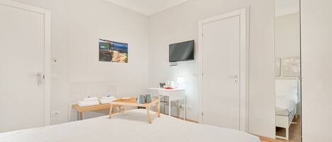 Una habitación de hotel con cama, escritorio, silla, televisor y armario.