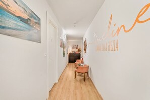 A hallway with a dining area, a painting on the wall, and a sign with text. - [Timeline Modern] 5Terre by ferry (La Spezia)
