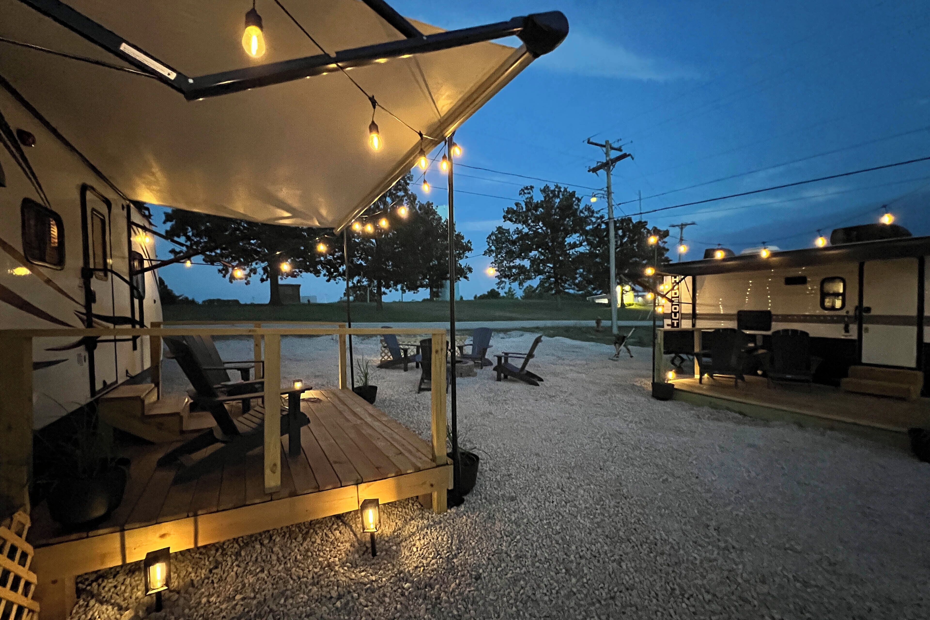 Un véhicule récréatif doté d’une terrasse couverte, de sièges d’extérieur et de guirlandes lumineuses.