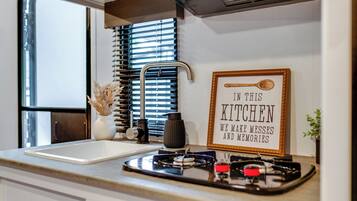 A compact kitchen with a sink, a framed sign, and a window with blinds.