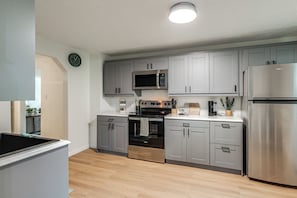 A modern kitchen with grey cabinets, stainless steel appliances, and a wooden floor. - Quiet Dayton Monthly Retreat, Near Hospitals (Dayton)