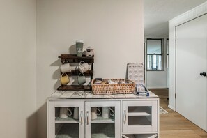 Zona cuina amb taulell de marbre, espai de cafè amb tasses i una tassa de cafè, i un cartell que enumera tipus de te.