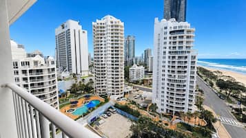 Un edificio residencial alto con varios balcones, una piscina y vistas a la playa.