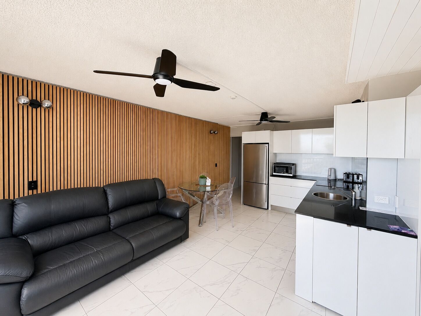 Cocina moderna con armarios blancos, un refrigerador de acero inoxidable y una encimera negra.