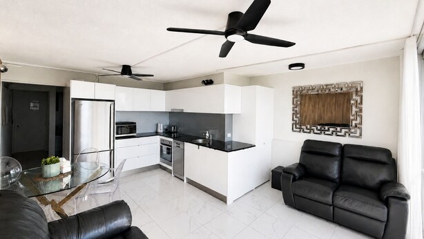 Una sala de estar moderna con un sofá de cuero negro, una mesa de centro de vidrio y un sofá cama de cuero negro.