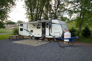 A Freedom Express RV parked on a gravel surface with a picnic table nearby.
