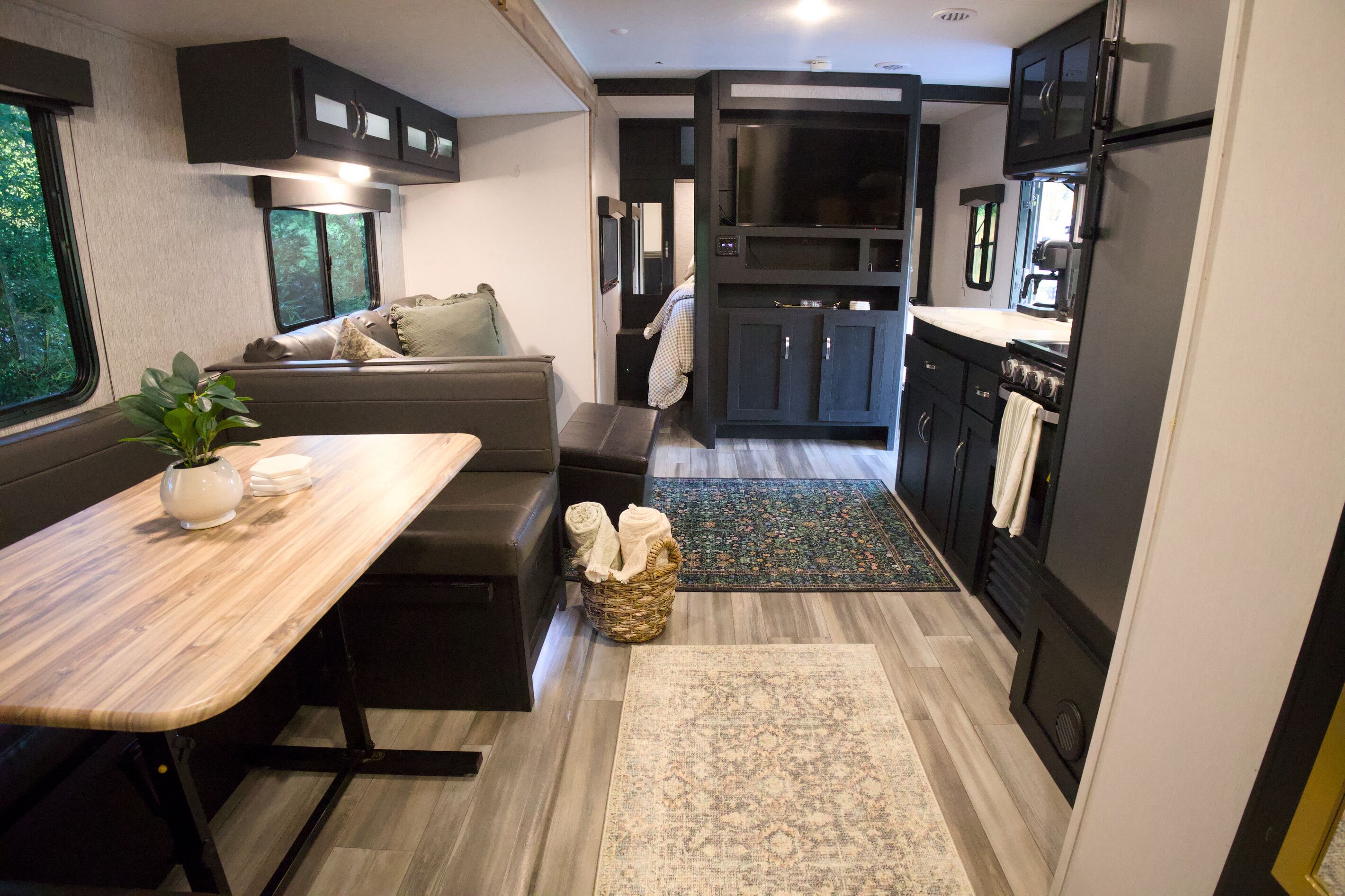Un intérieur de camping-car compact comprenant un coin repas, des sièges, une cuisine et une petite salle de bain.