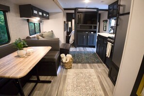 Ein kompaktes Wohnmobil-Interieur mit Essbereich, Sitzgelegenheiten, einer Küche und einem kleinen Bad.