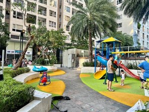 A playground with slides and swings, surrounded by greenery and buildings. - Teddy Apartment (Ho Chi Minh City)