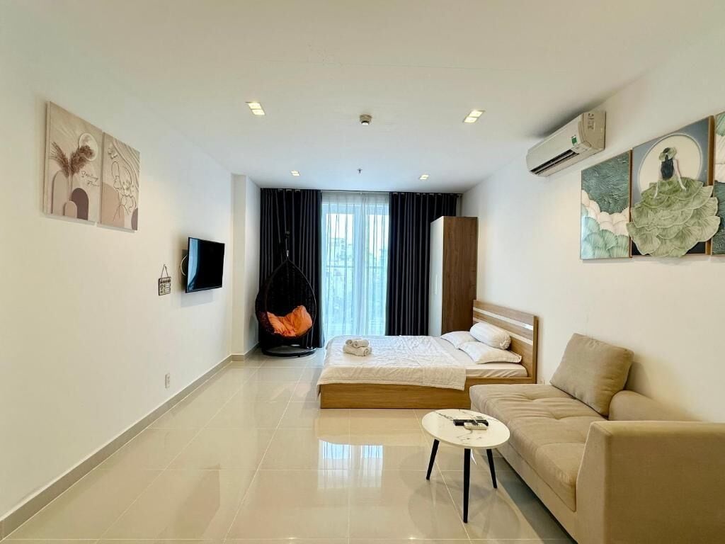 A modern hotel room with a large bed, a sofa, a small table, and artwork on the walls.
