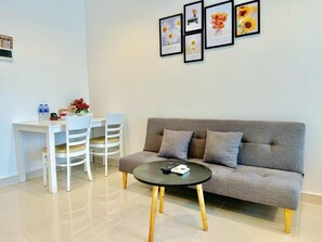 A modern living room with a grey sofa, a round coffee table, and a dining area with white chairs. - Teddy Apartment (Ho Chi Minh City)