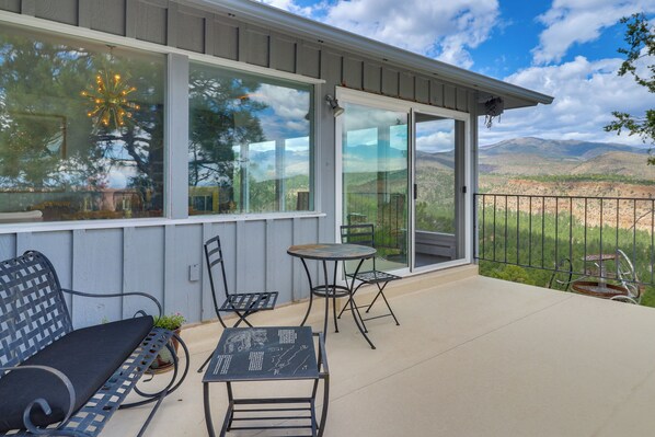 A covered patio with a table and chairs, a bench, and a view of a mountainous landscape. - Mid-Century Home on Canyon-Edge with Stellar Views (Los Alamos)