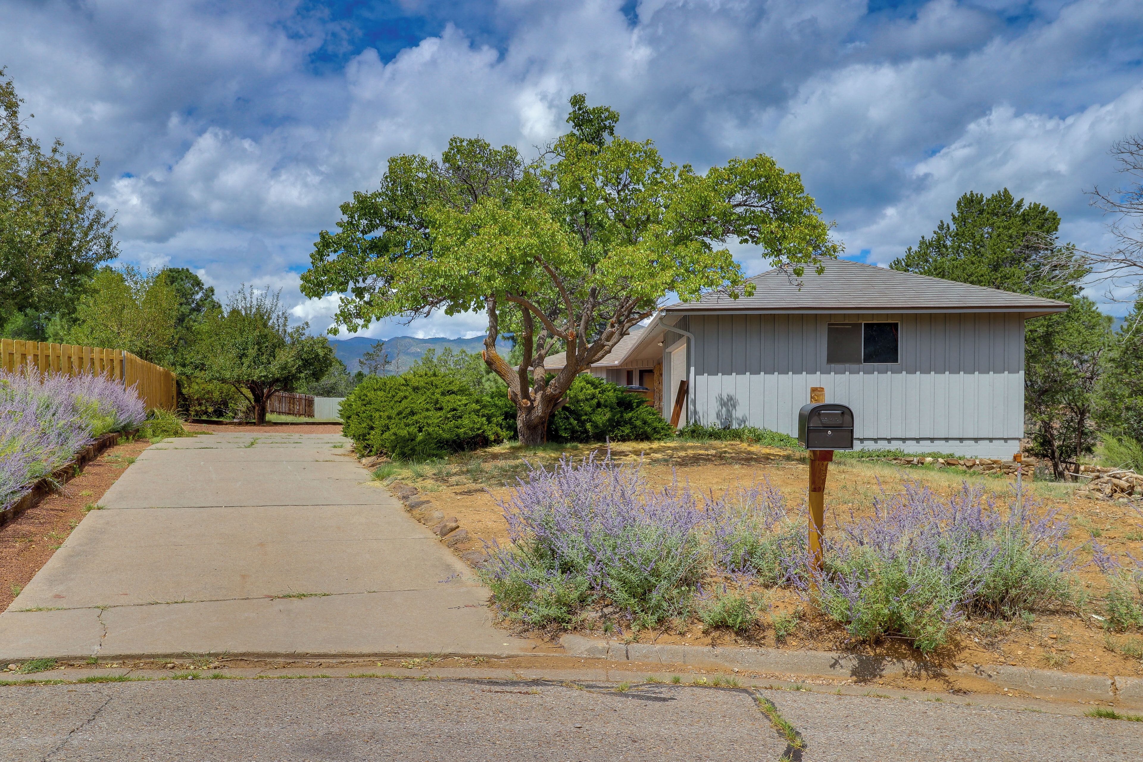 A residential property with a paved driveway, a mailbox, and a small house with a sloped roof.