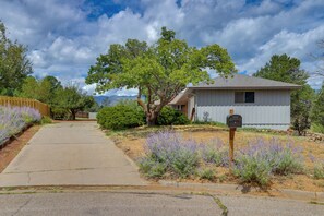 A residential property with a paved driveway, a mailbox, and a small house with a sloped roof.