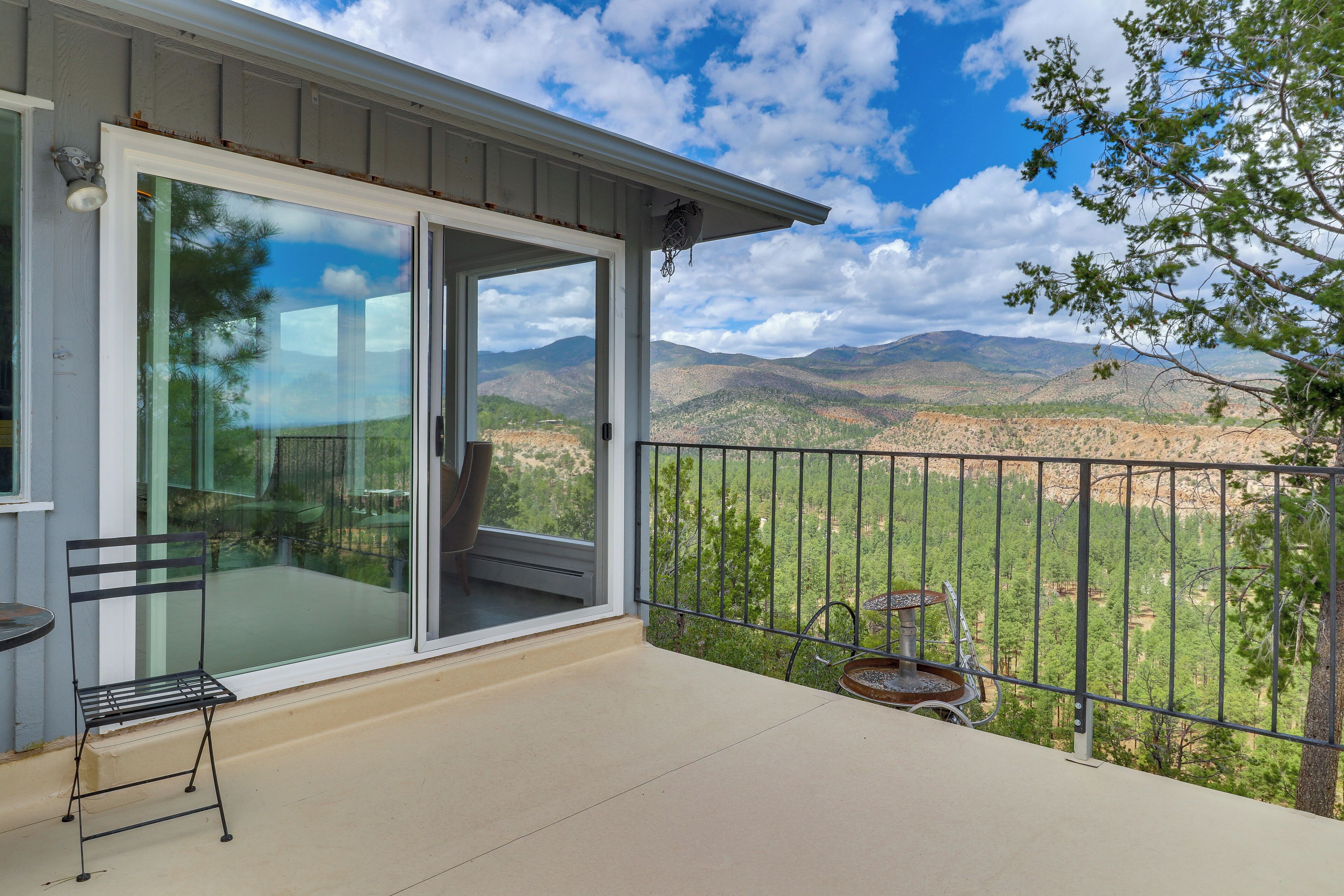 A balcony with a glass door leading to a patio area, a metal chair, and a small table.