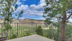 Ein Balkon mit Metallgeländer mit Blick auf eine gebirgige Landschaft mit spärlicher Vegetation.